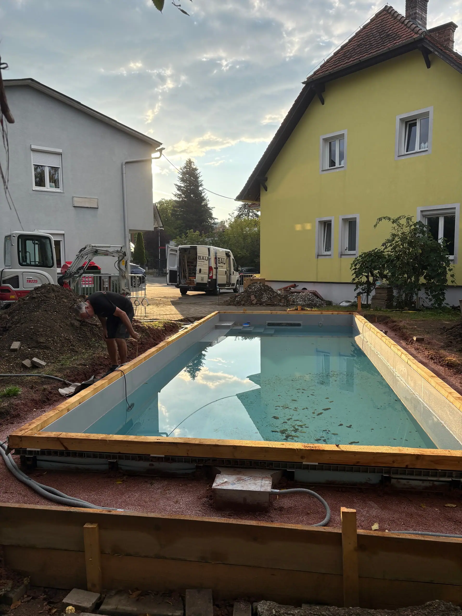 Mit Wasser gefülltes Becken, rundherum Holzschalung und Erdreich