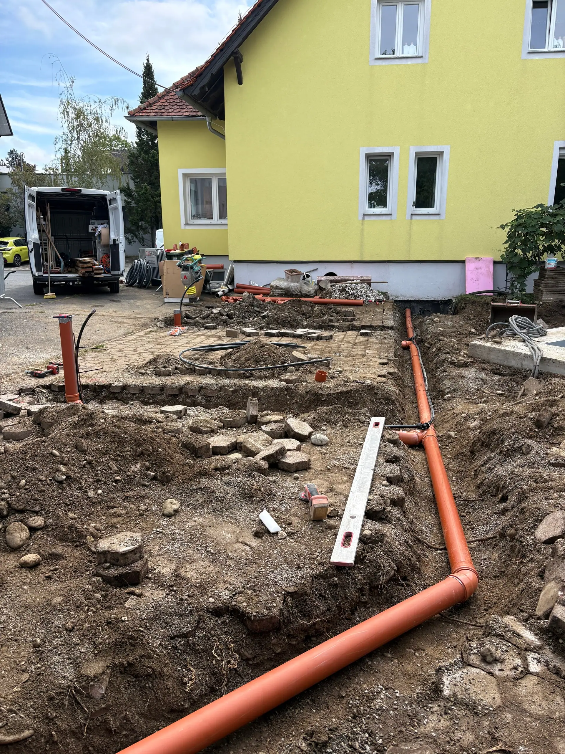 Orange Rohre im offenen Graben zwischen Pool und Haus