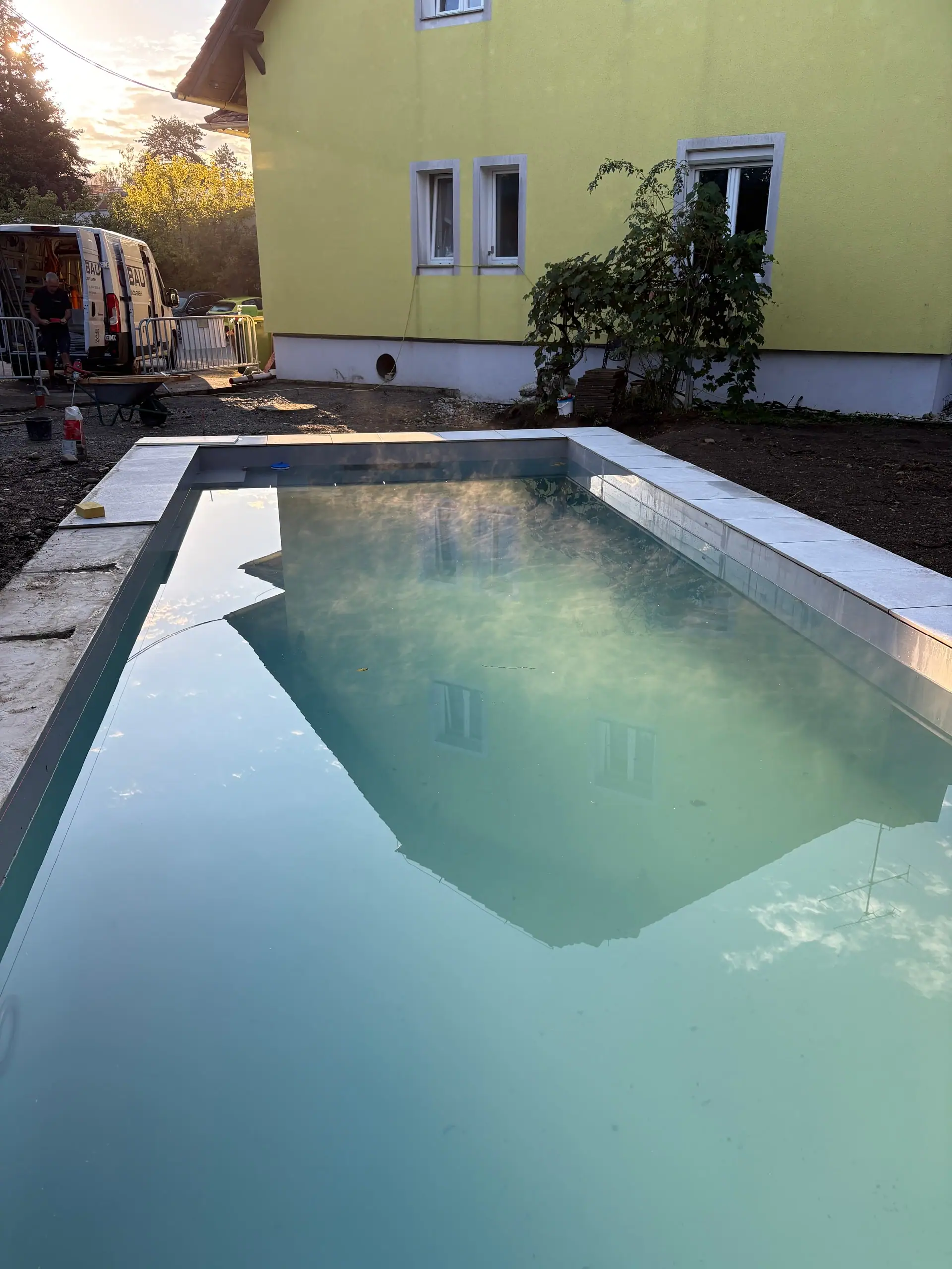 Neu gesetzter Pool mit Wasser vor einem gelben Haus
