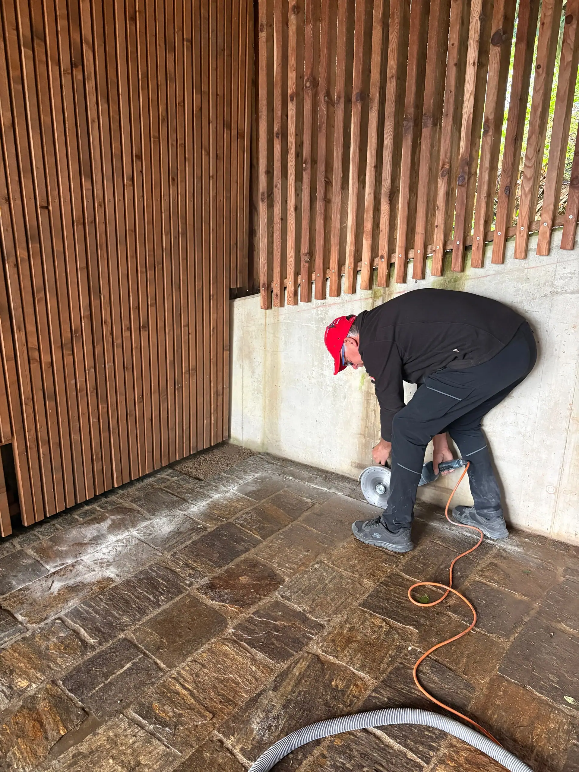 Arbeiter schneidet mit dem Winkelschleifer in einen alten Steinboden