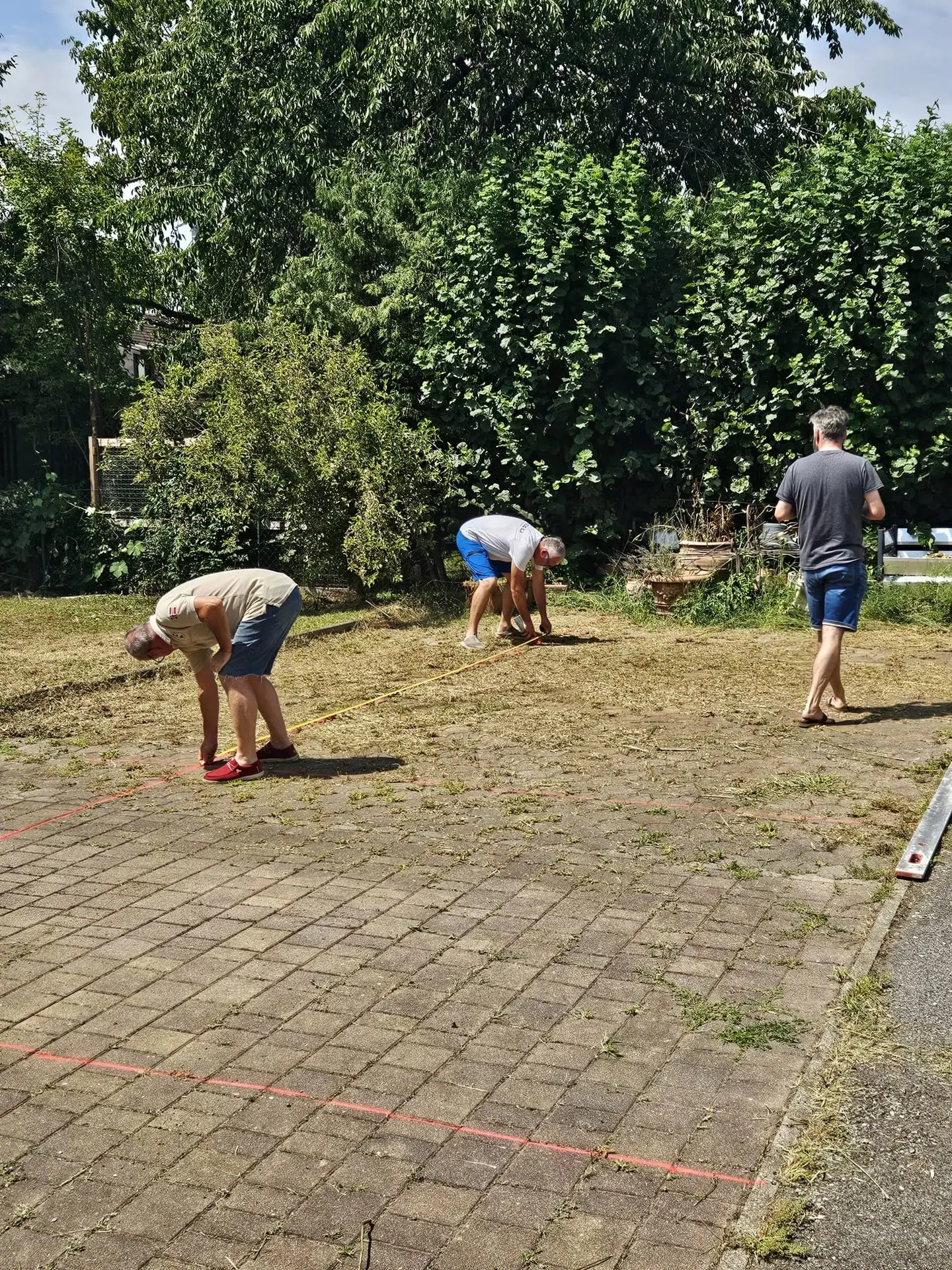 Drei Arbeiter bei Pflasterarbeiten in einem Garten