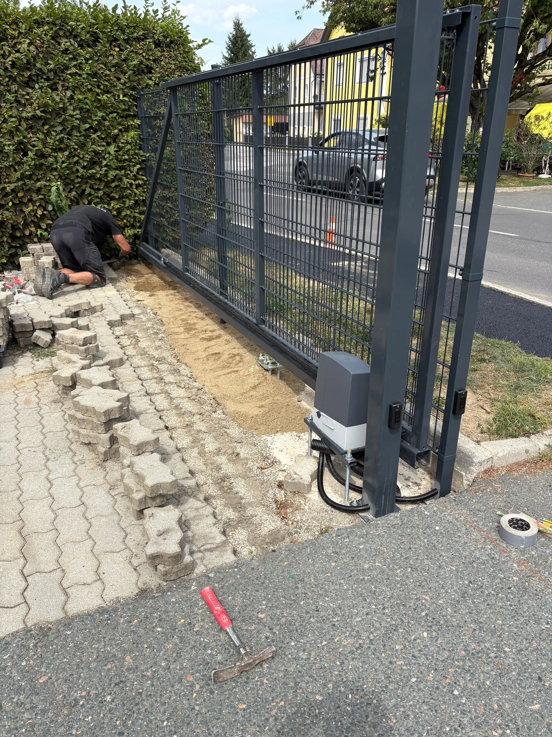 Arbeiter passt das Pflaster neben dem Torantrieb an