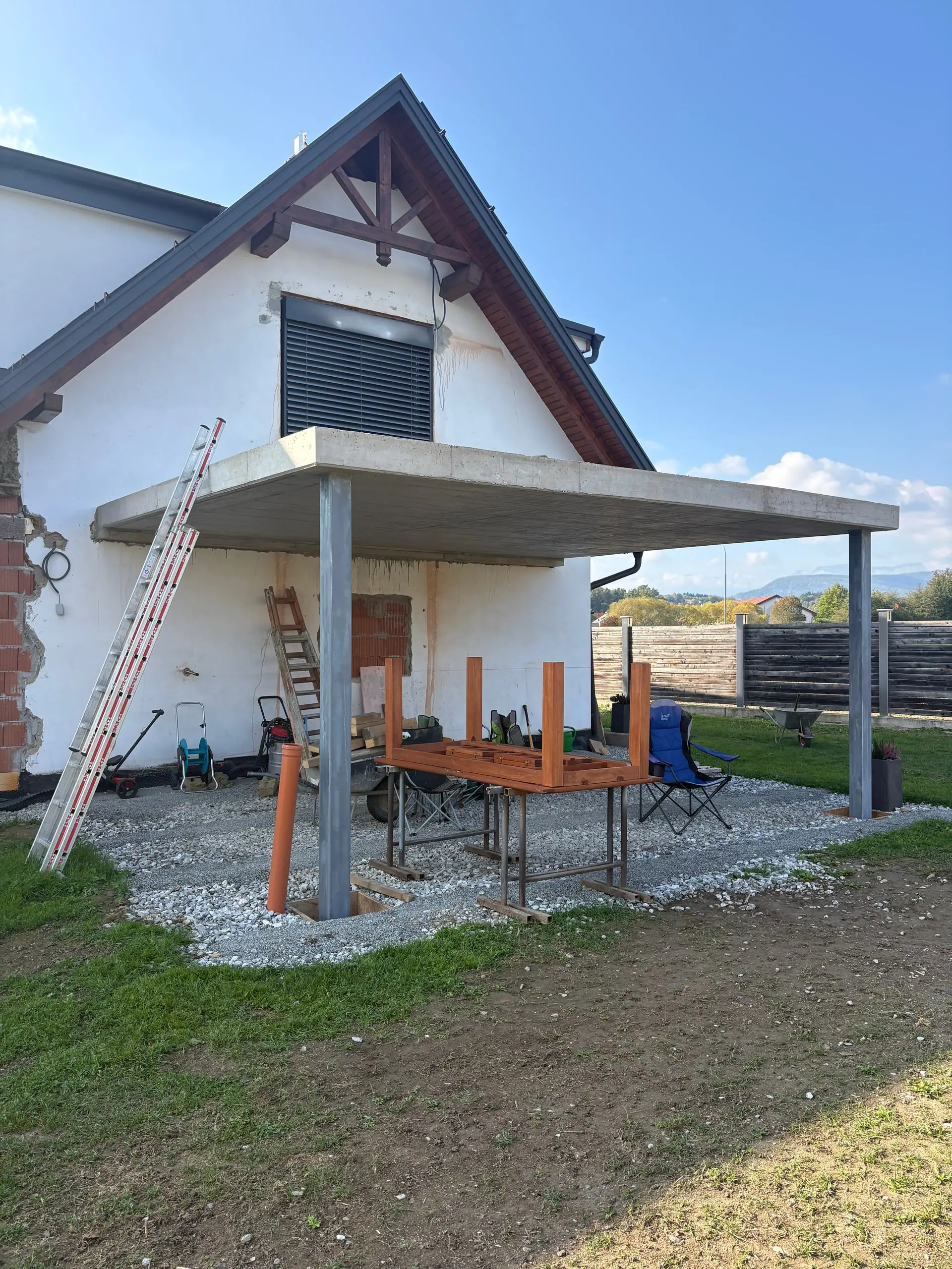 Fertige Betondecke auf einer Stahlstütze über der Terrasse eines weißen Hauses
