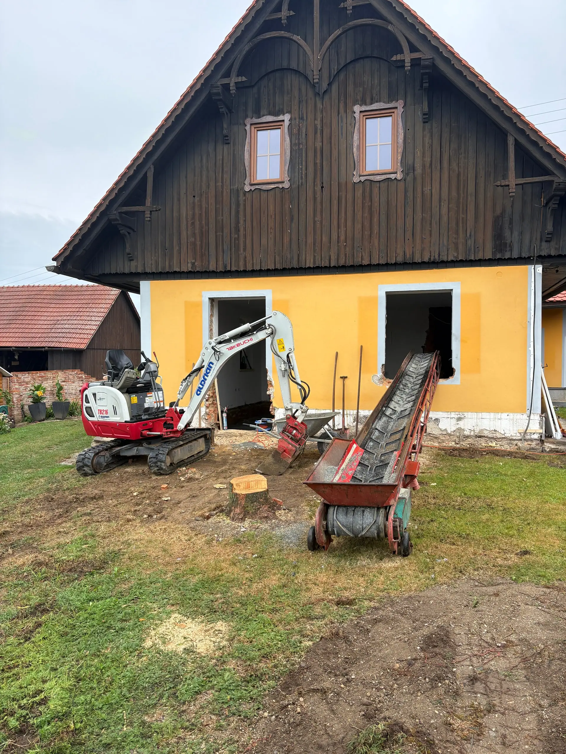 Minibagger hebt neben dem gelben Haus aus
