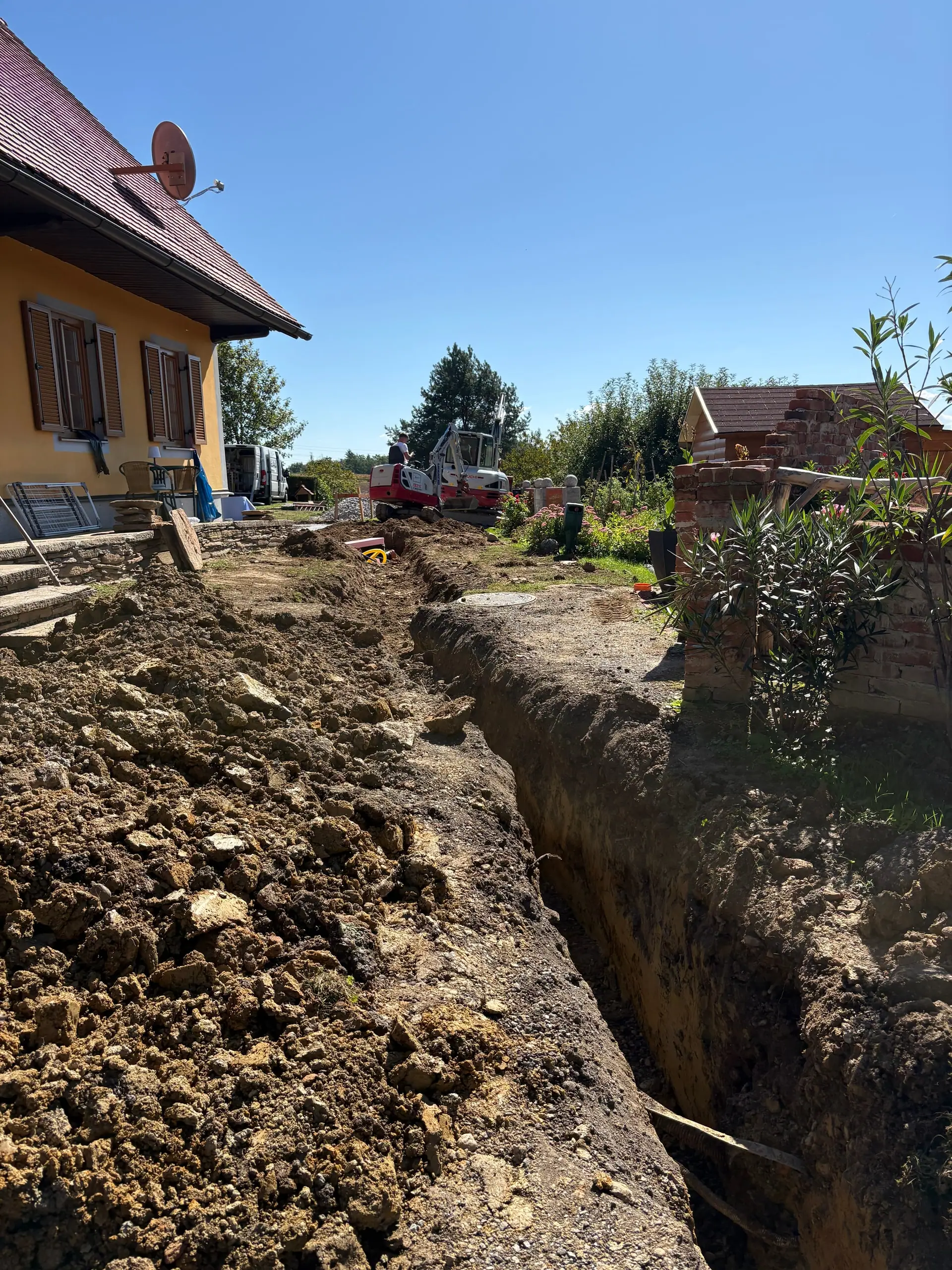 Offener Graben mit Rohr neben der Baugrube