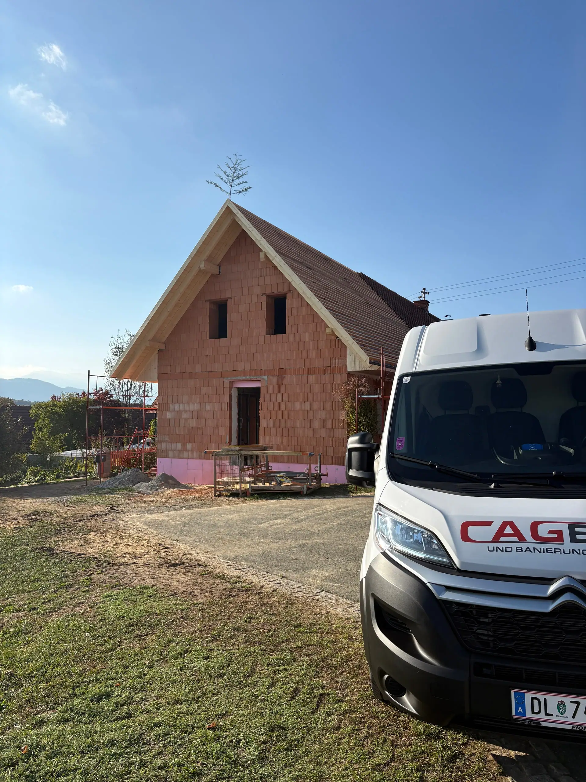 Zubau in Ziegelbauweise mit Giebel, davor der Bus von CAG BAU