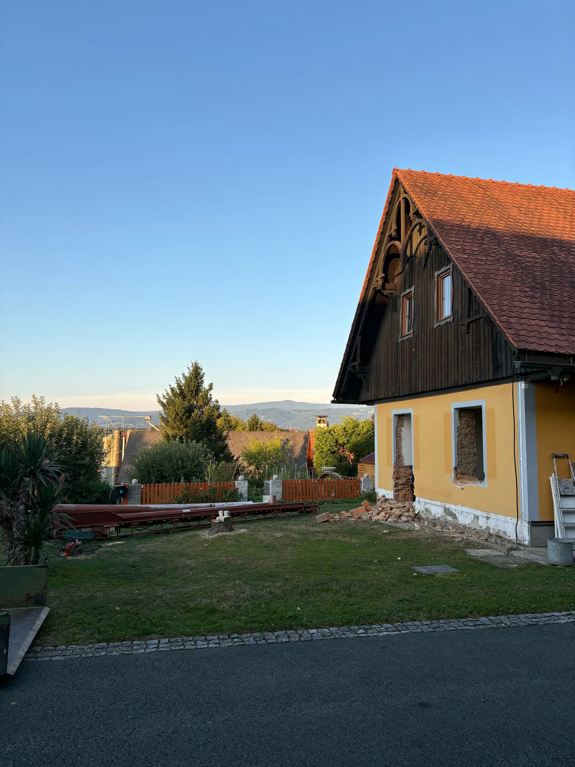 Das gelbe Wohnhaus mit dunklem Holzgiebel vor dem Zubau